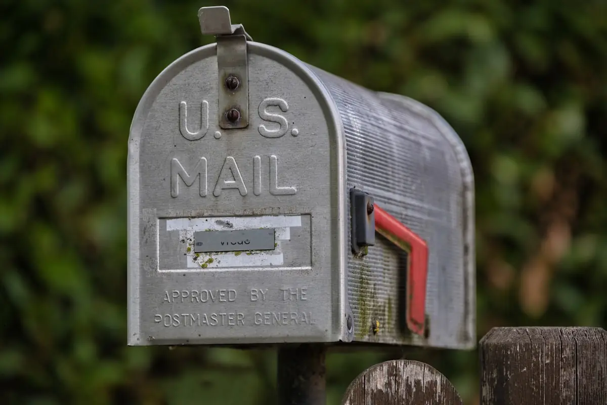 Weathered metal curbside mailbox on a post with its signal flag raised