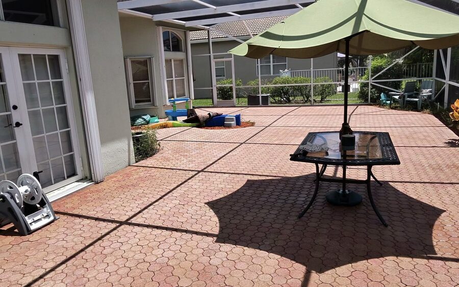Screened lanai after cleaning with the house wall and rear doors alongside the cleaned deck