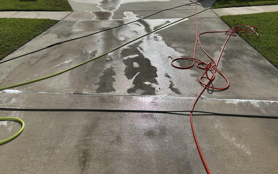 Concrete driveway during pressure washing with the surface wet and cleaning solution still working