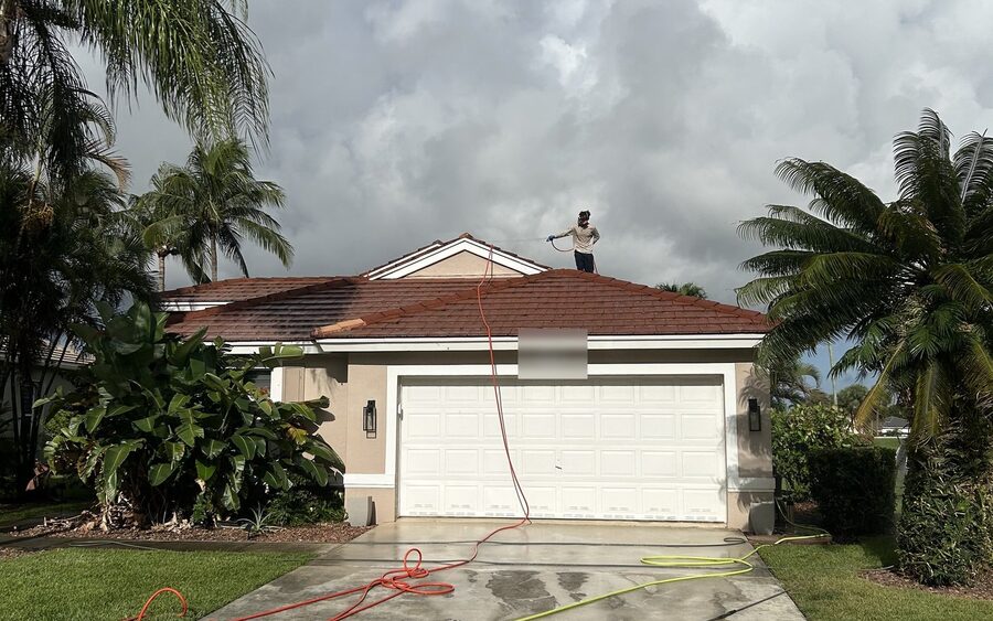 Technician on a tile roof applying low-pressure soft wash solution