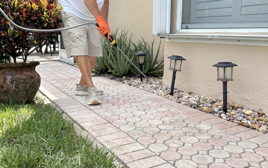 Technician cleaning a paver walkway with a low-pressure surface wand