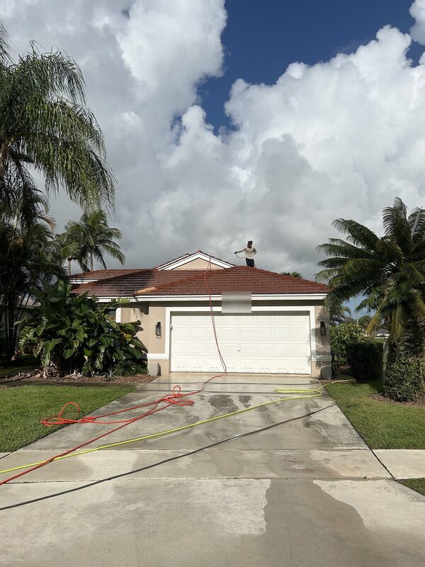 Technician on a tile roof applying low-pressure soft wash solution