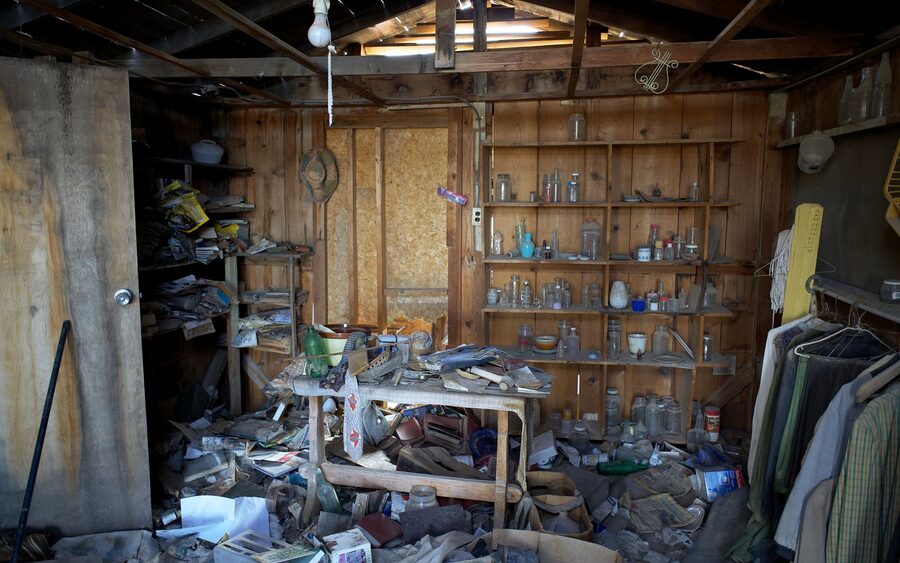 Cluttered shed interior packed with stored items, tools and debris