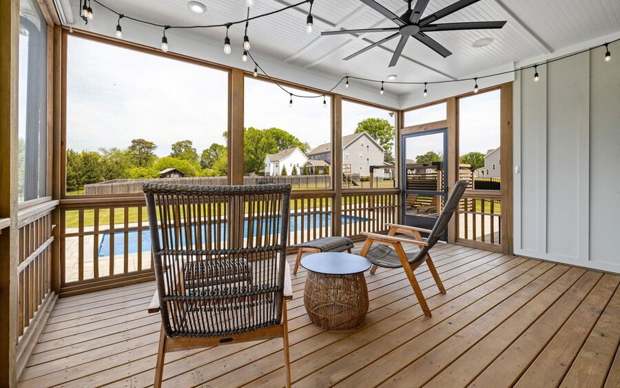 Screened porch with wicker furniture and a ceiling fan overlooking a backyard pool