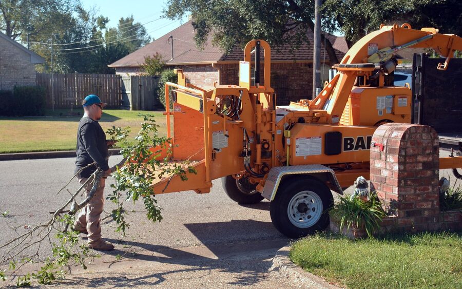 Cut branches being fed into a towed wood chipper on a residential street
