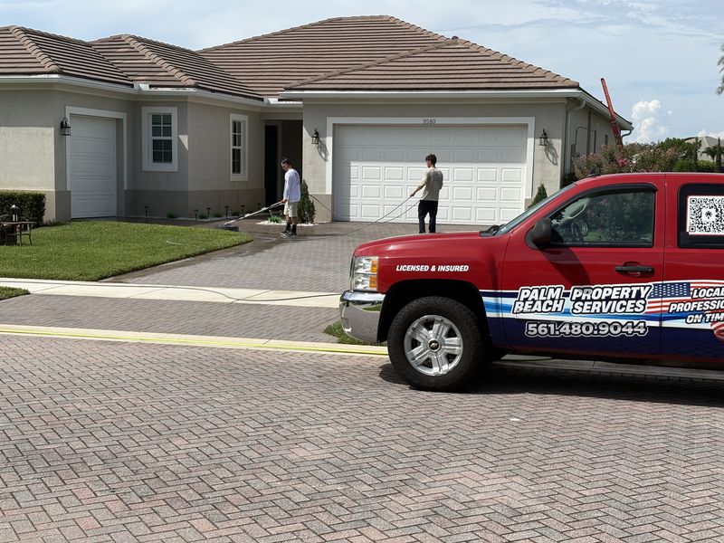 Palm Beach Property Services truck on site while crew surface cleans a paver driveway